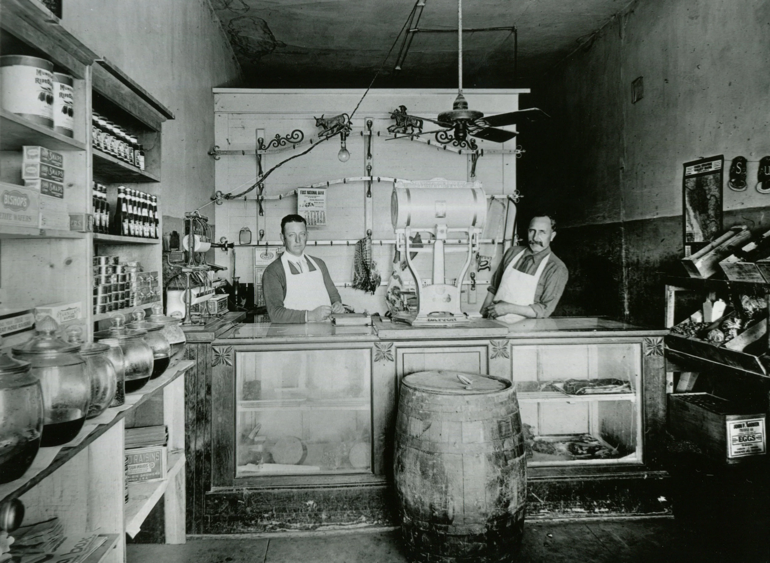 The writing on the back of this photograph reads: Prettyman's Market on Main St. Approximately 1/2 block west of Florence St. Don Prettyman Sr. on left and Ramon Andrade Jr. Circa 1920. 