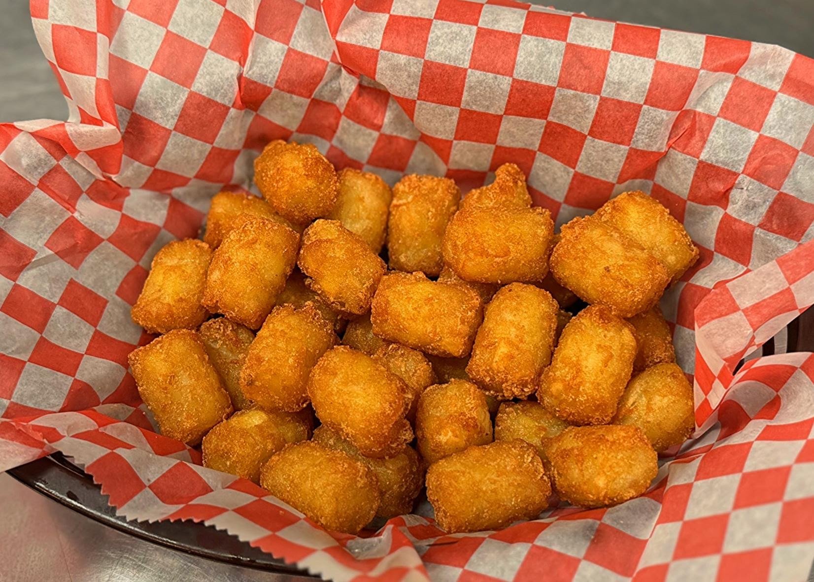 Basket of fried tater tots with red and white checkered paper lining.