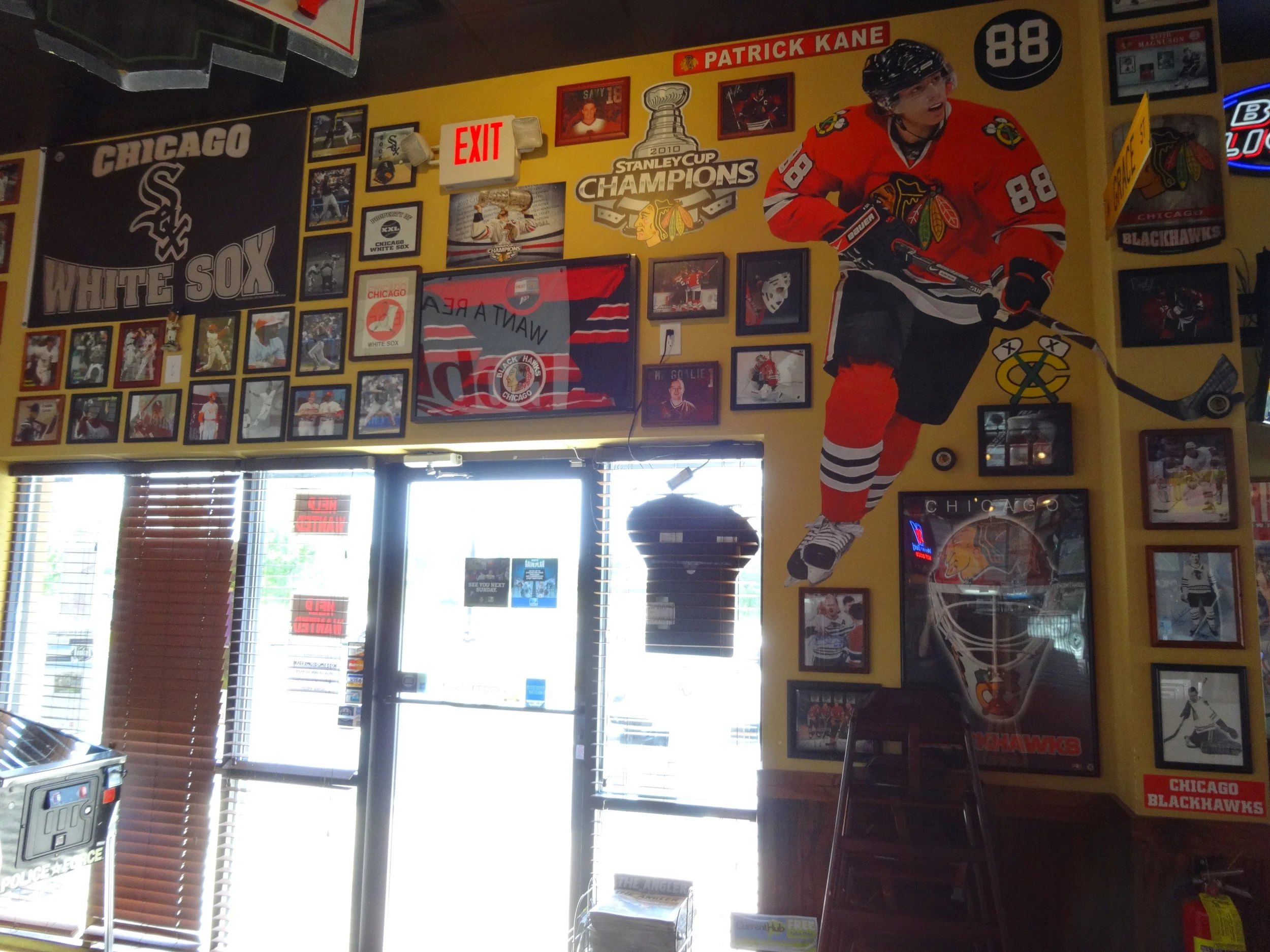 Wall decorated with Chicago White Sox and Chicago Blackhawks memorabilia, photos, and jerseys inside a sports restaurant or bar.