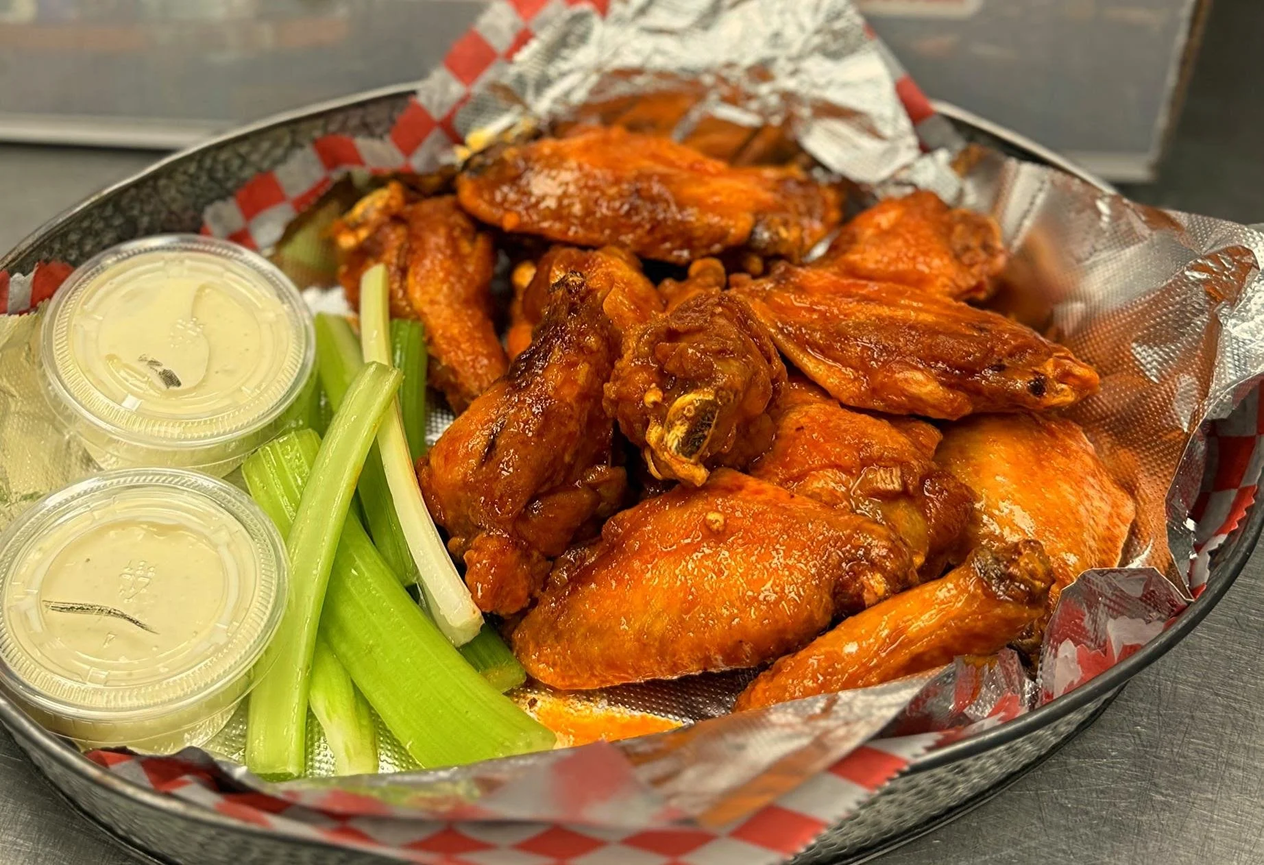 Basket of buffalo chicken wings with celery sticks and bleu cheese dressing.