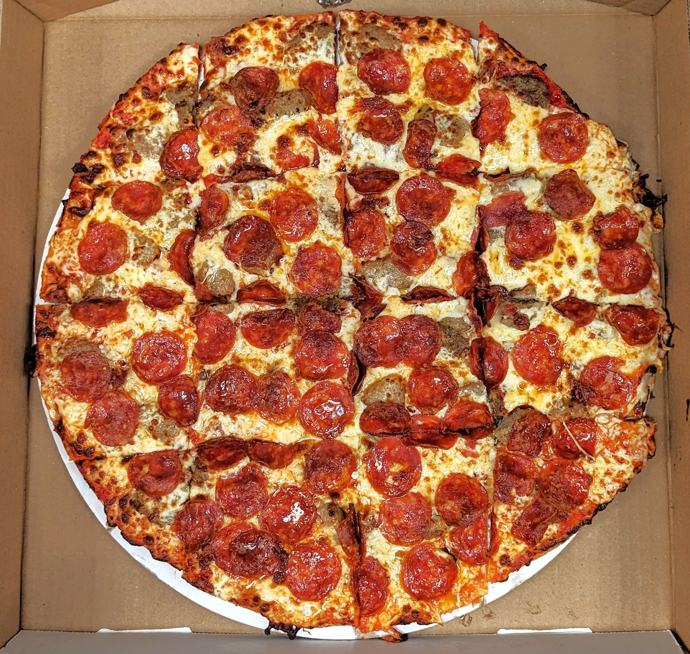 A large pepperoni pizza in a cardboard box, with a portion cut out.