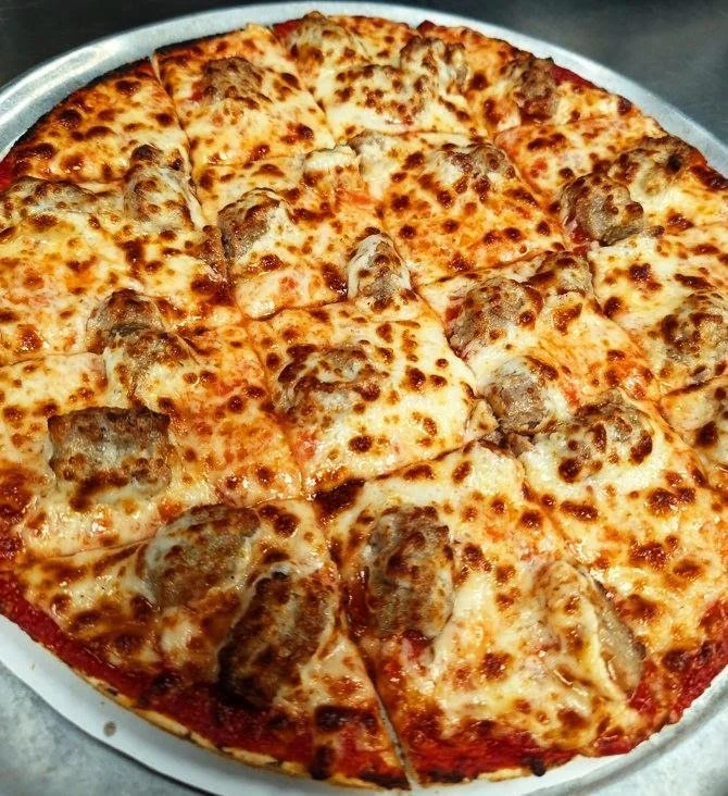 Cheese pizza with sausage toppings on a round tray.
