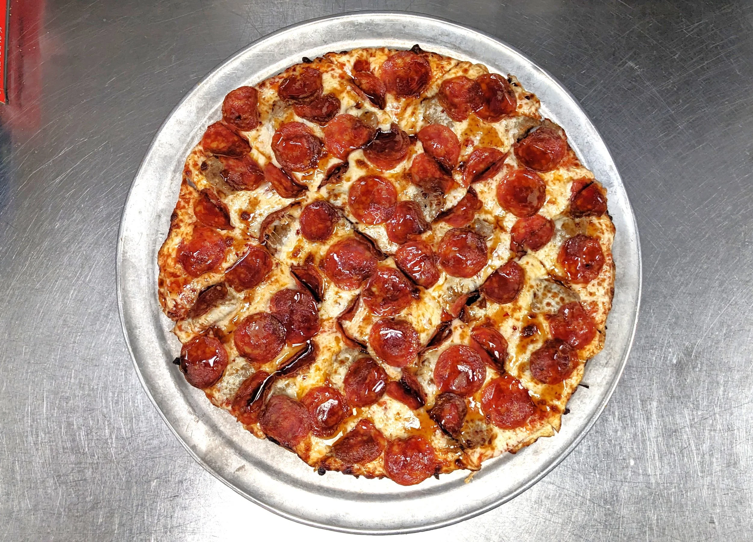 A pepperoni pizza with cheese and sausage on a metal tray