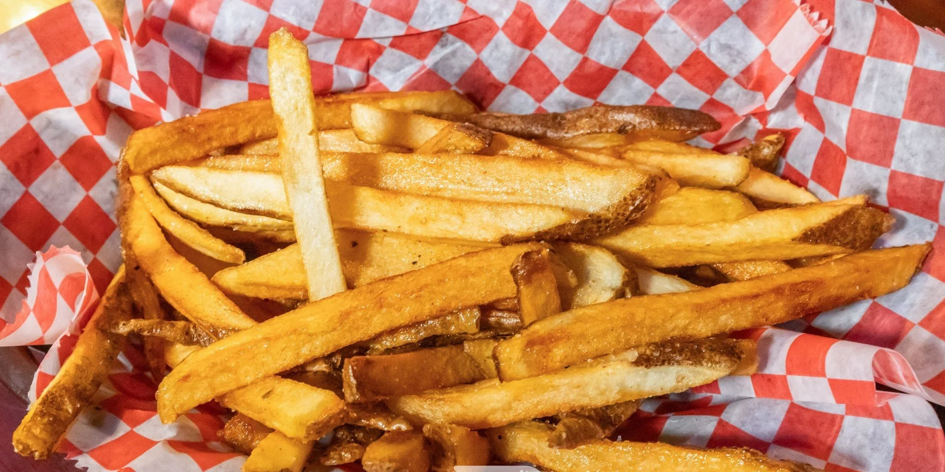 A serving of French fries in red and white checkered paper.