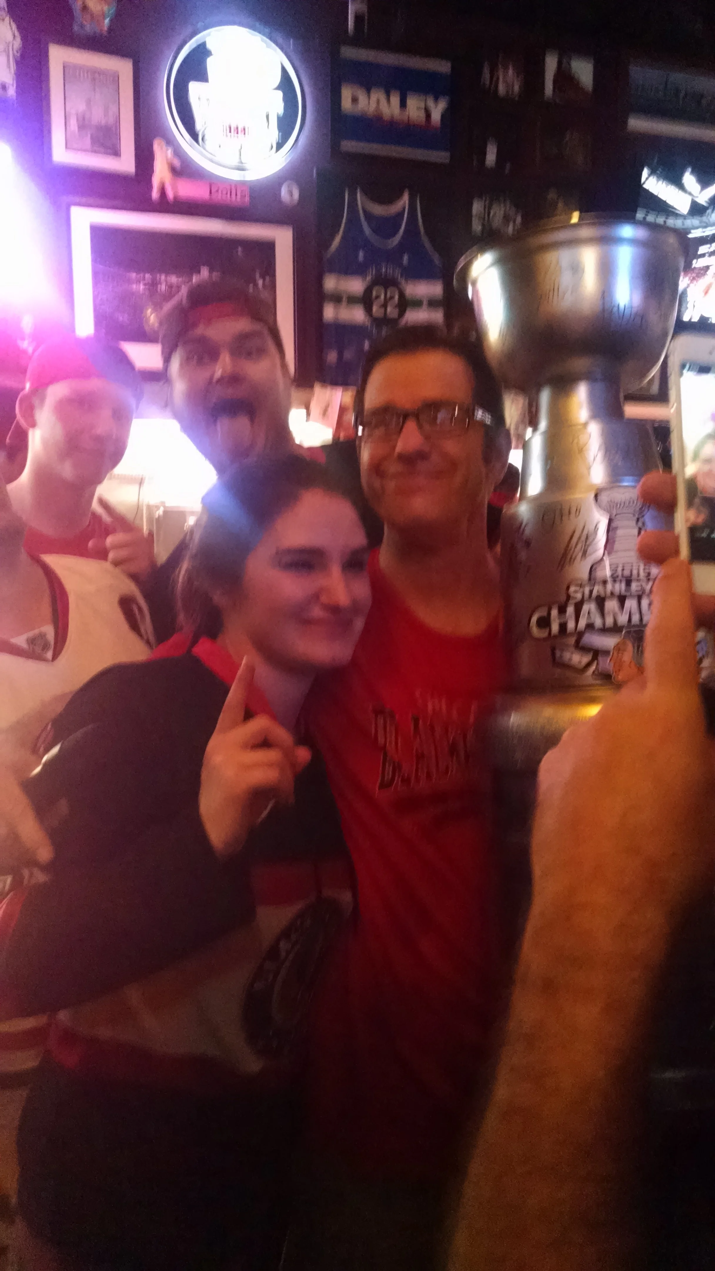 A group of sports fans celebrating with a trophy in a sports bar.