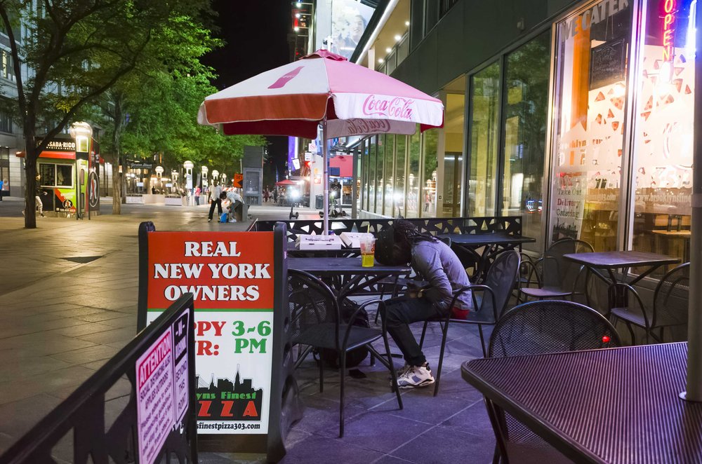  A gentleman rests his head on the table of an outdoor restaurant on 16th St Mall in Denver.  