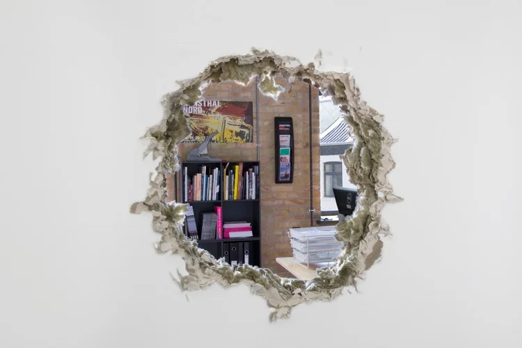 A THING IS A HOLE IN THE THING IT IS NOT, 2015, Dimensions variable Existing doorway in partition wall, wooden beams, dry wall, filler, insulation, white paint, various office furniture and personal effects, staff