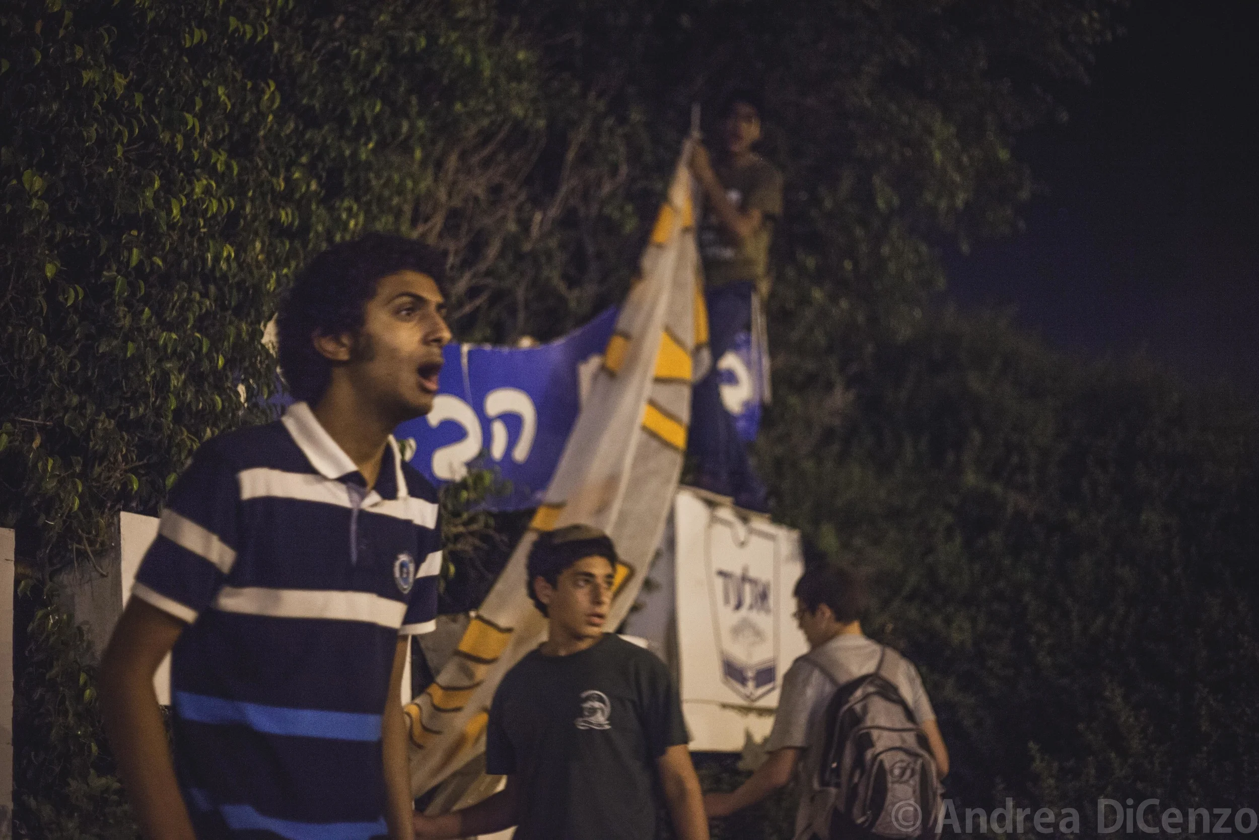 A group of boys from the Israeli settlement of El Ad cautiously addresses strangers passing by as they try to erect a large homemade banner on the evening the bodies of the three missing Israeli teenagers were discovered.