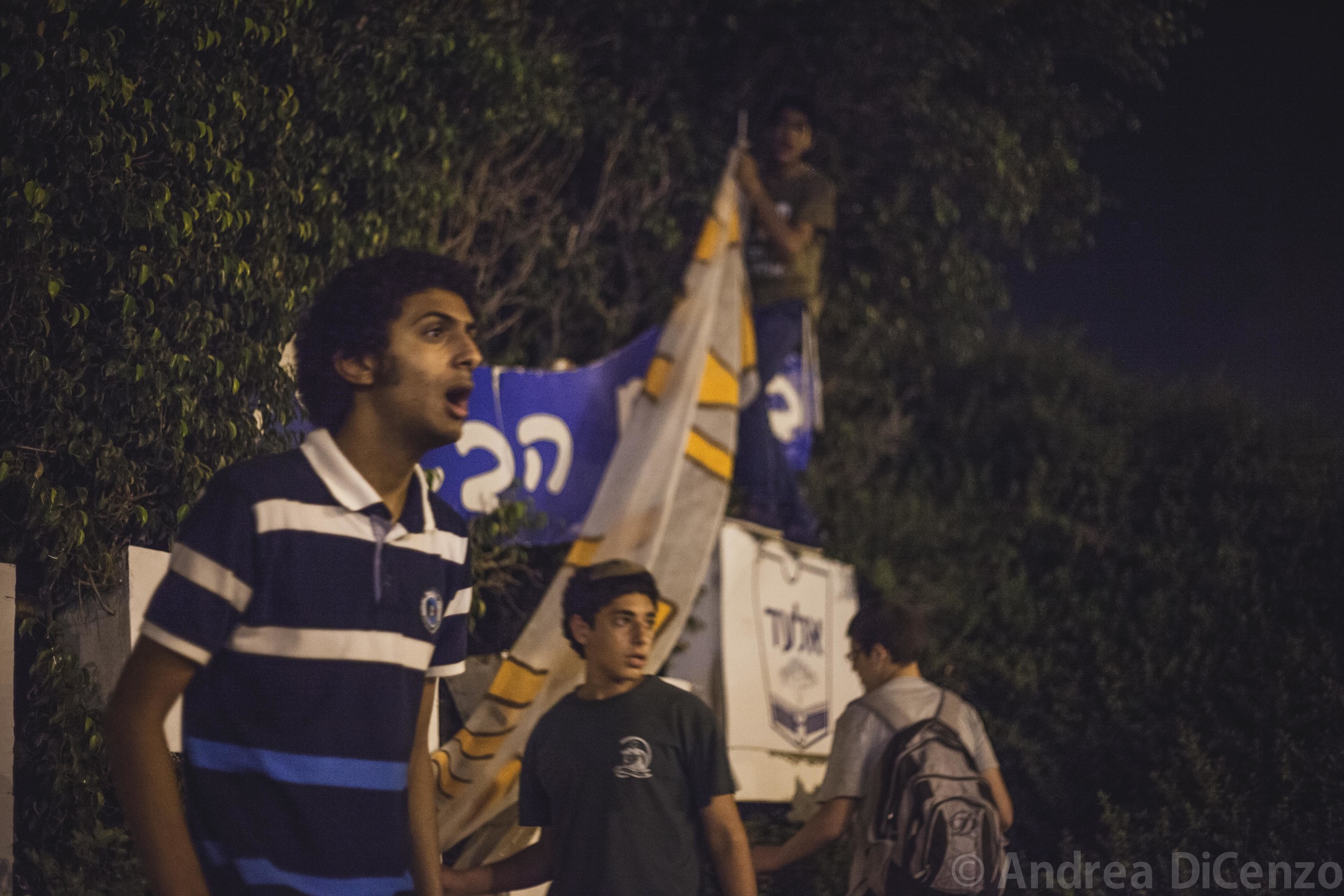  A group of boys from the Israeli settlement of El Ad&nbsp;cautiously addresses&nbsp;strangers passing by as they try to erect a large homemade banner on the evening the bodies of the three missing Israeli teenagers were discovered. 