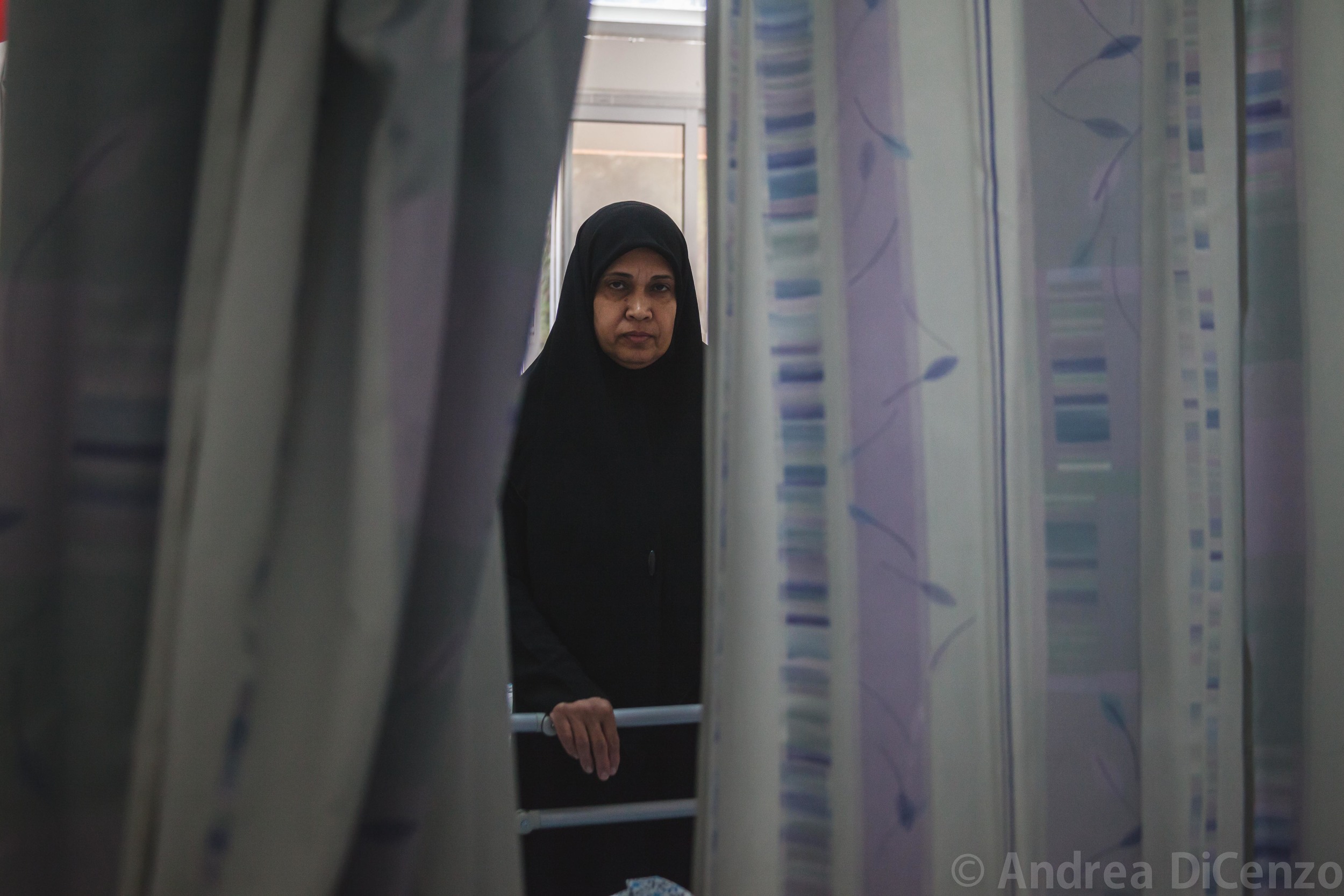  The aunt of Ahad, an injured child from Gaza, peers through the curtains of her niece's hospital bed.&nbsp;Ahad was granted special passage from the Strip to an East Jerusalem hospital because of the severity of her condition. Each patient is allowe