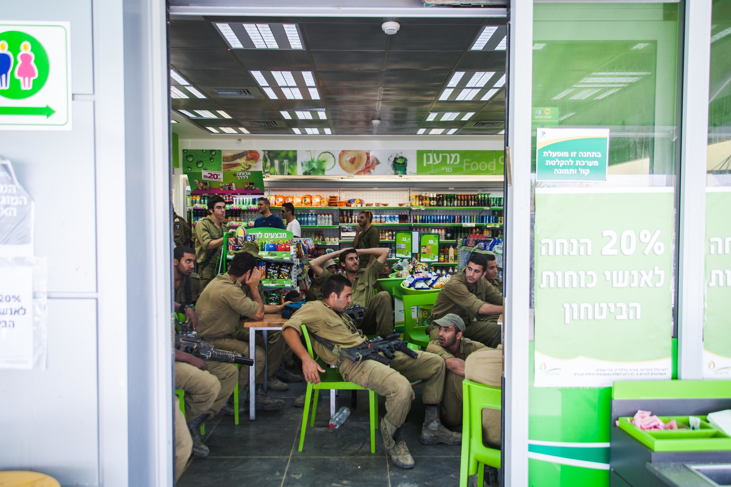  Soldiers watch the news and eat ice-cream in a gas station close to their base on the border of Gaza/Israel. 