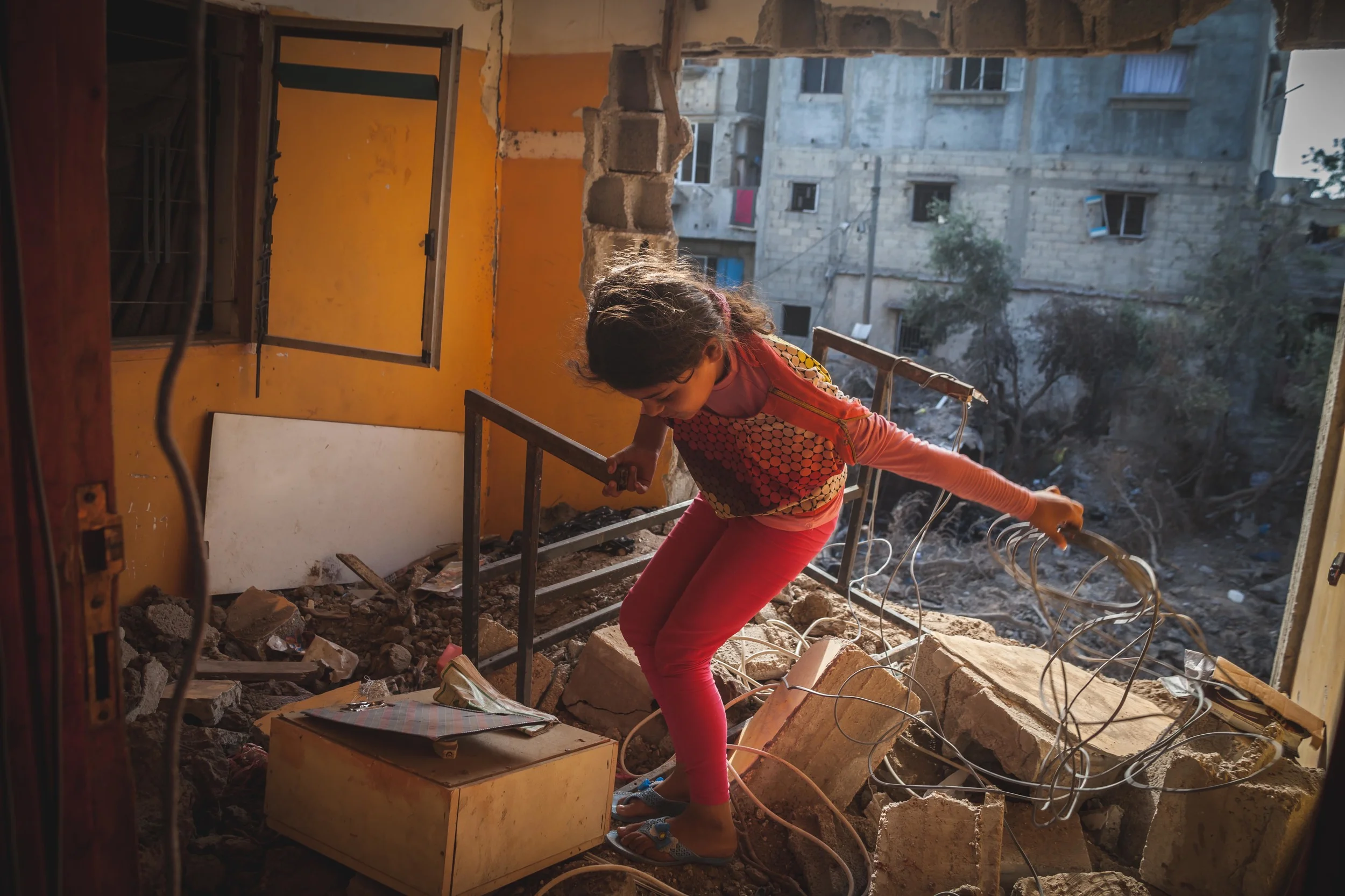 A young girl climbs over the rubble that fills what once was her and her siblings bedroom. Beit Hanoun, Gaza Strip.