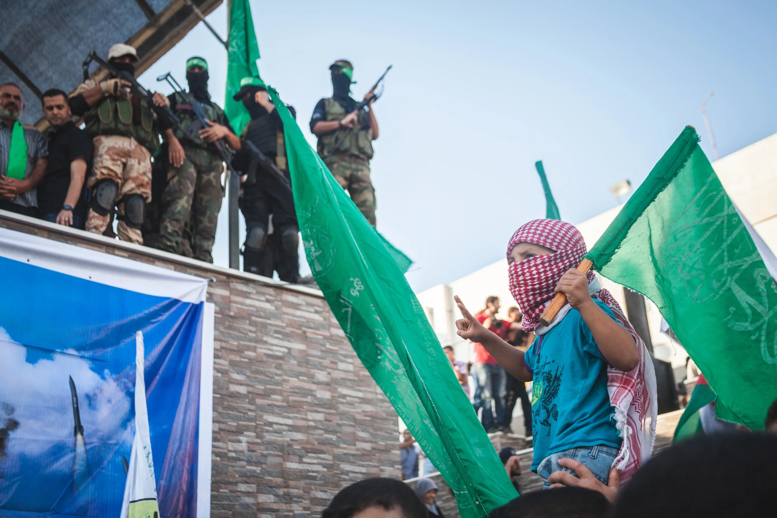 Hamas militants face a cheering crowd to celebrate the end of the Israeli/Gaza bloody war as a child looks on in Gaza City.