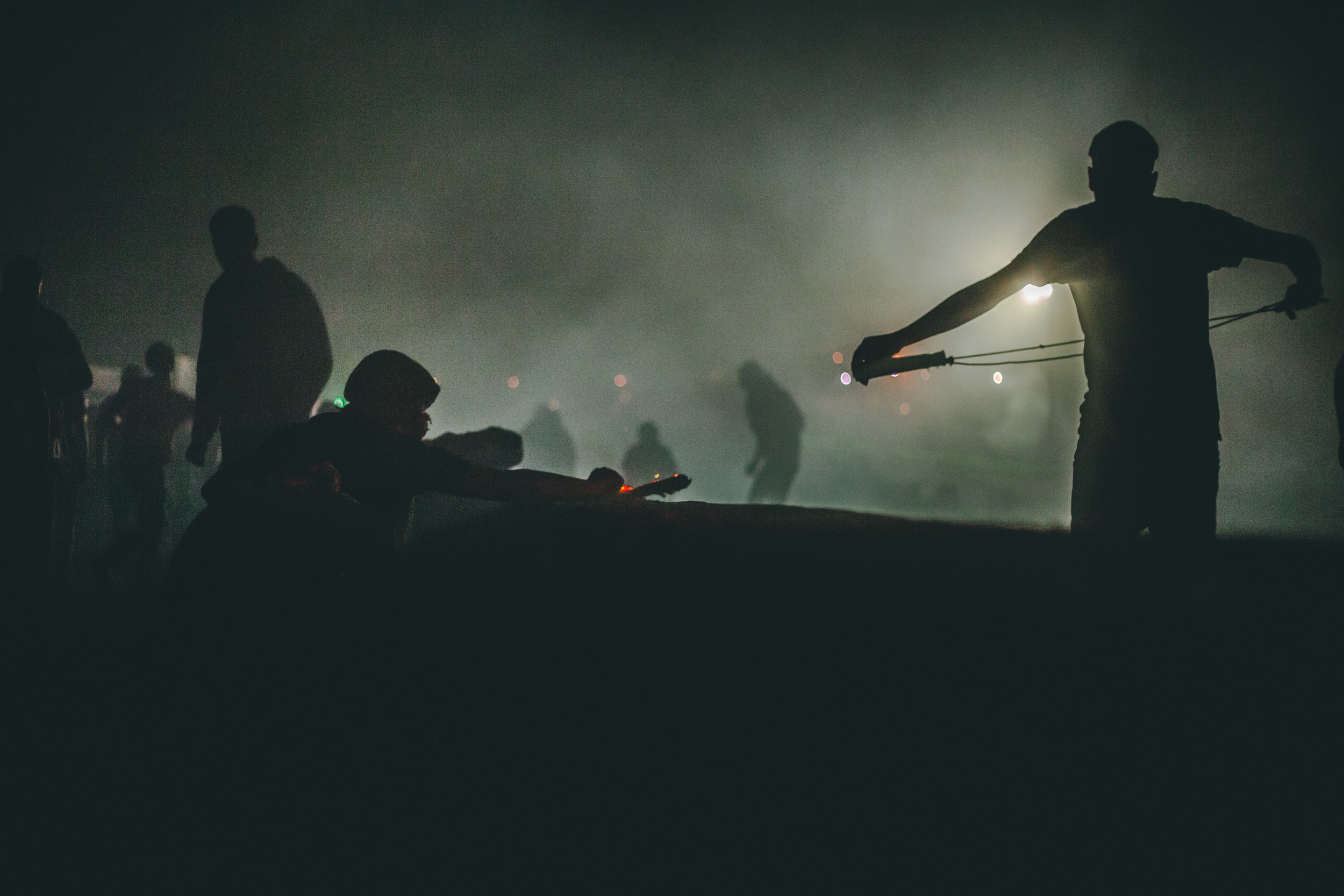  A Palestinian protestor preps his sling shot in a silhouette of tear-gas and smoke.&nbsp; 