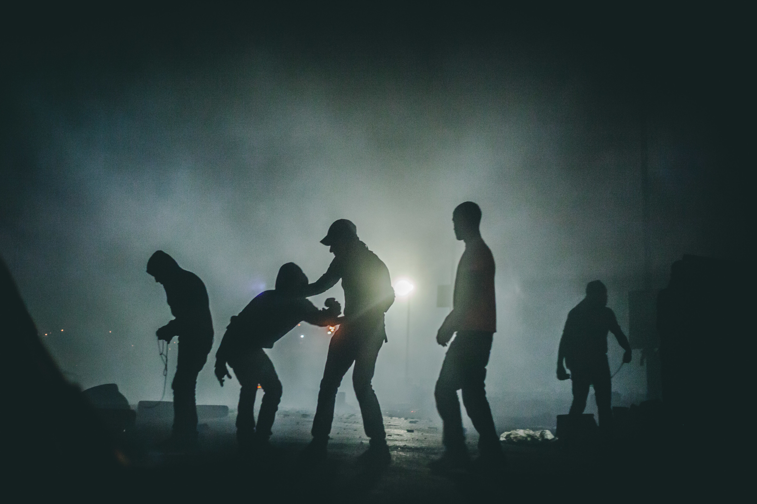  Protesters gather rocks and adjust slingshots in the fog of tear-gas and smoke that has descended Qalandia checkpoint. 48Thousand March. 23rd July 2014.&nbsp; 