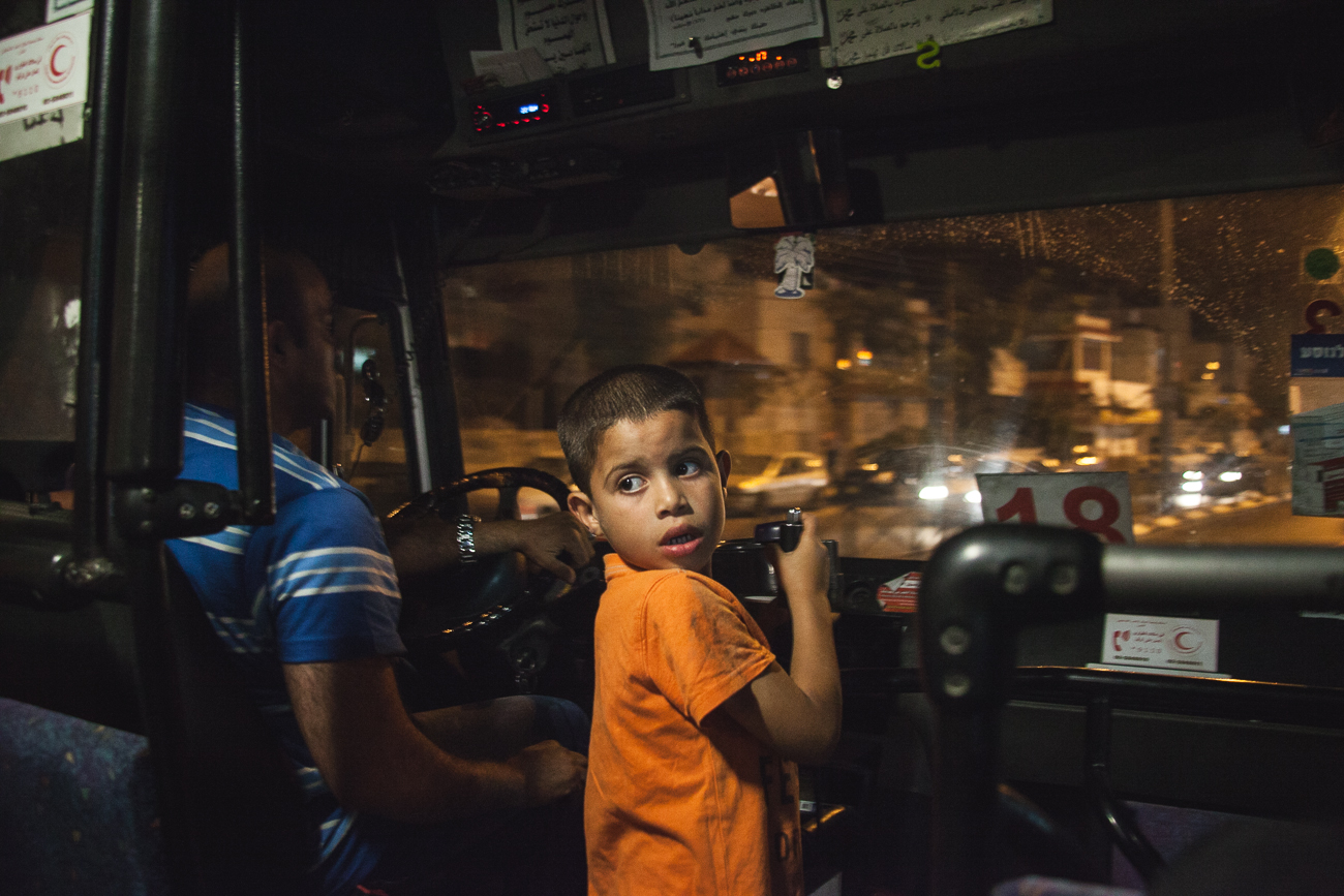  A little boy looks back at commuters on a packed bus in Ramallah as the radio reports the discovery of the three missing Israeli teen's bodies in the West Bank.&nbsp; 