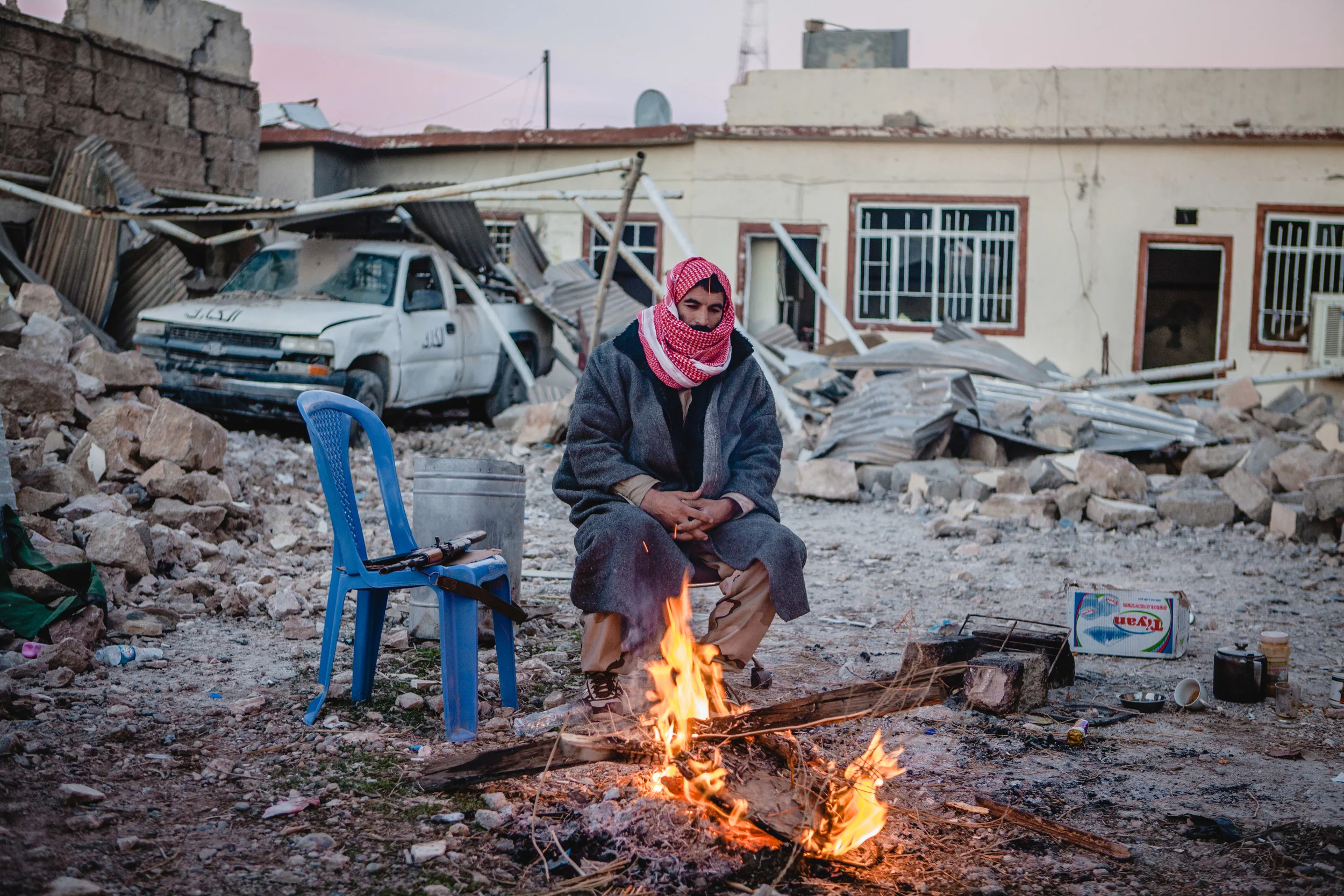 A peshmerga solider warms himself by a fire after sitting guard during the night.