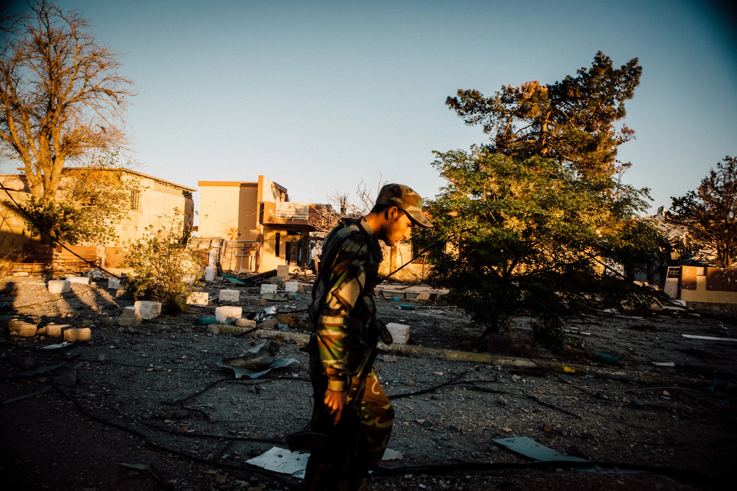 The sunsets on a Peshmerga solider as he walks through the streets of Sinjar City.