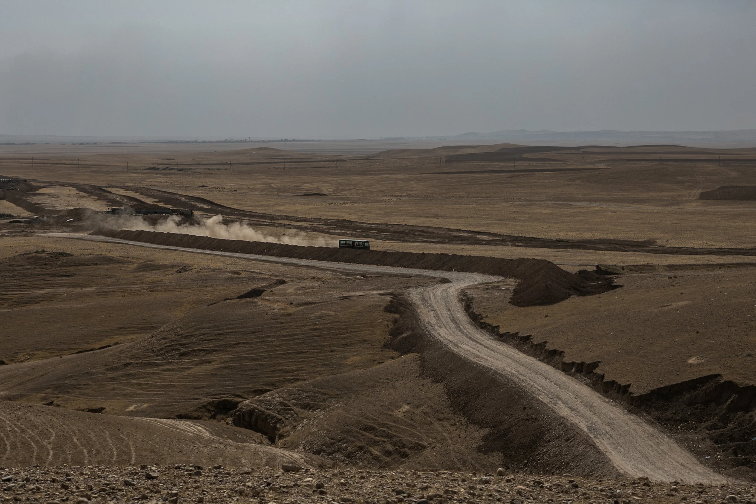 A Peshmerga transport bus kicks up dust along the Gwar frontline. Nineveh plains.