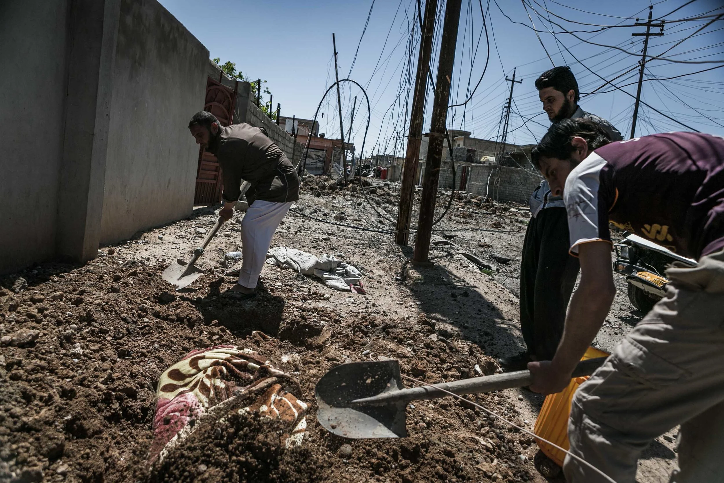 Civilians find some soft ground to be able to bury the body of one of their relatives who died trying to flee the fighting in 17 Tammuz neighborhood, western Mosul. 