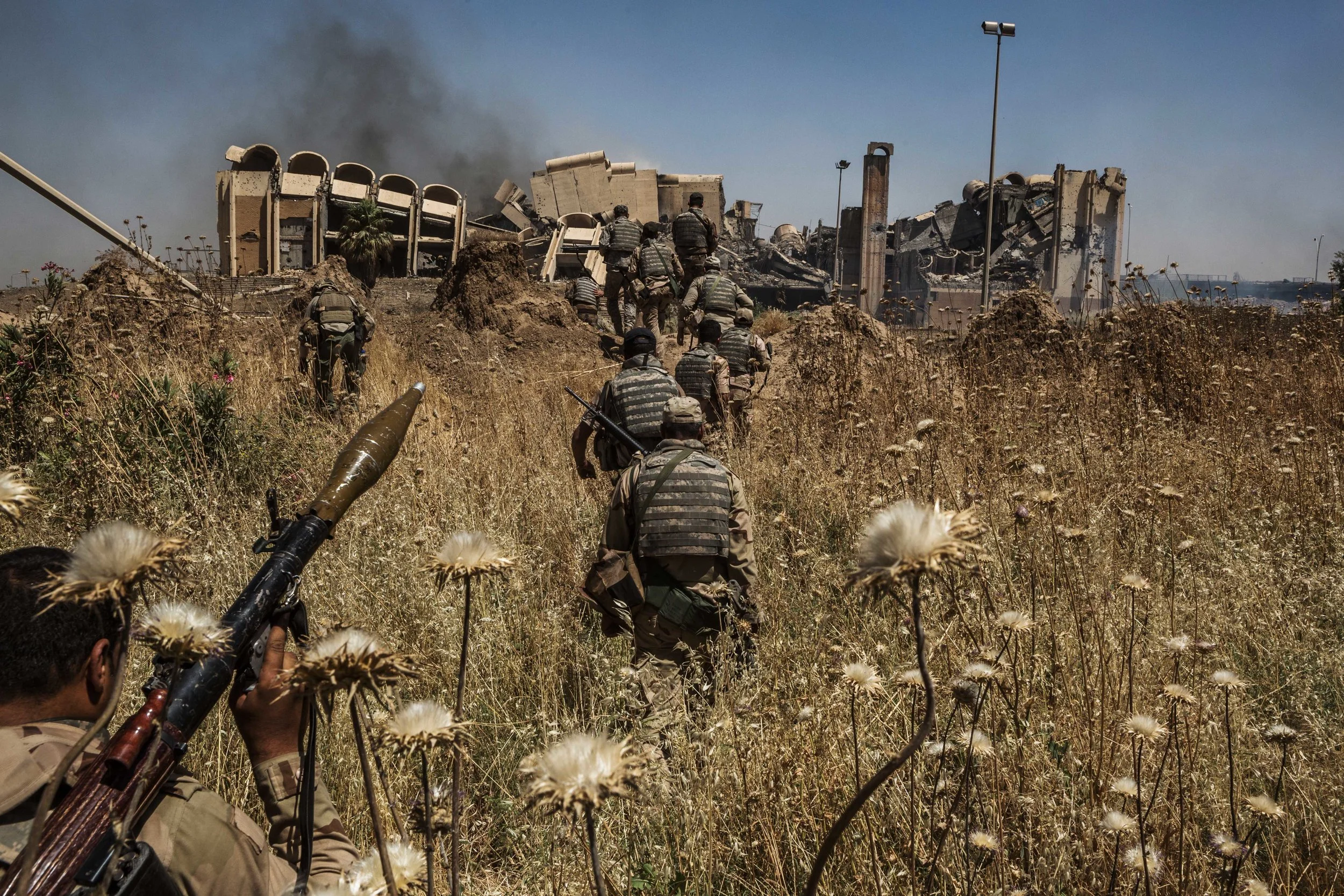 Smoke plumes from an airstrike in al-Shifa neighborhood rise up behind members of the Iraqi army’s 9th and 16th division during a new northwestern push to rid the Islamic State from their last remaining strongholds in Mosul. Only five districts in western Mosul are under Islamic State control, but the forces believe the final districts will be the hardest and most violent fighting in the old military campaign.