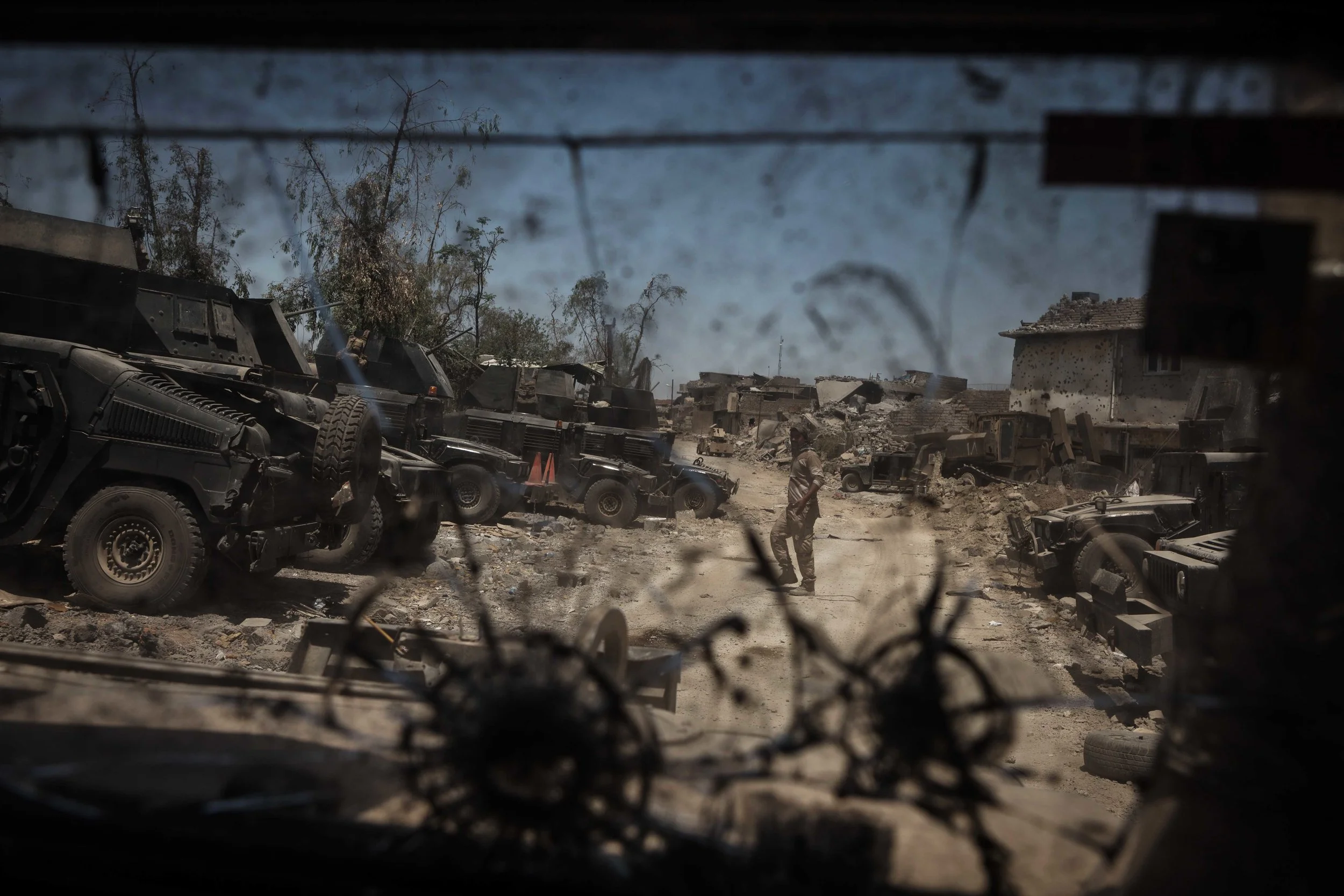 A soldier in the Iraqi army, seen through the shattered glass of a Humvee, walks along the frontline in al-Zinjili neighborhood in western Mosul.
