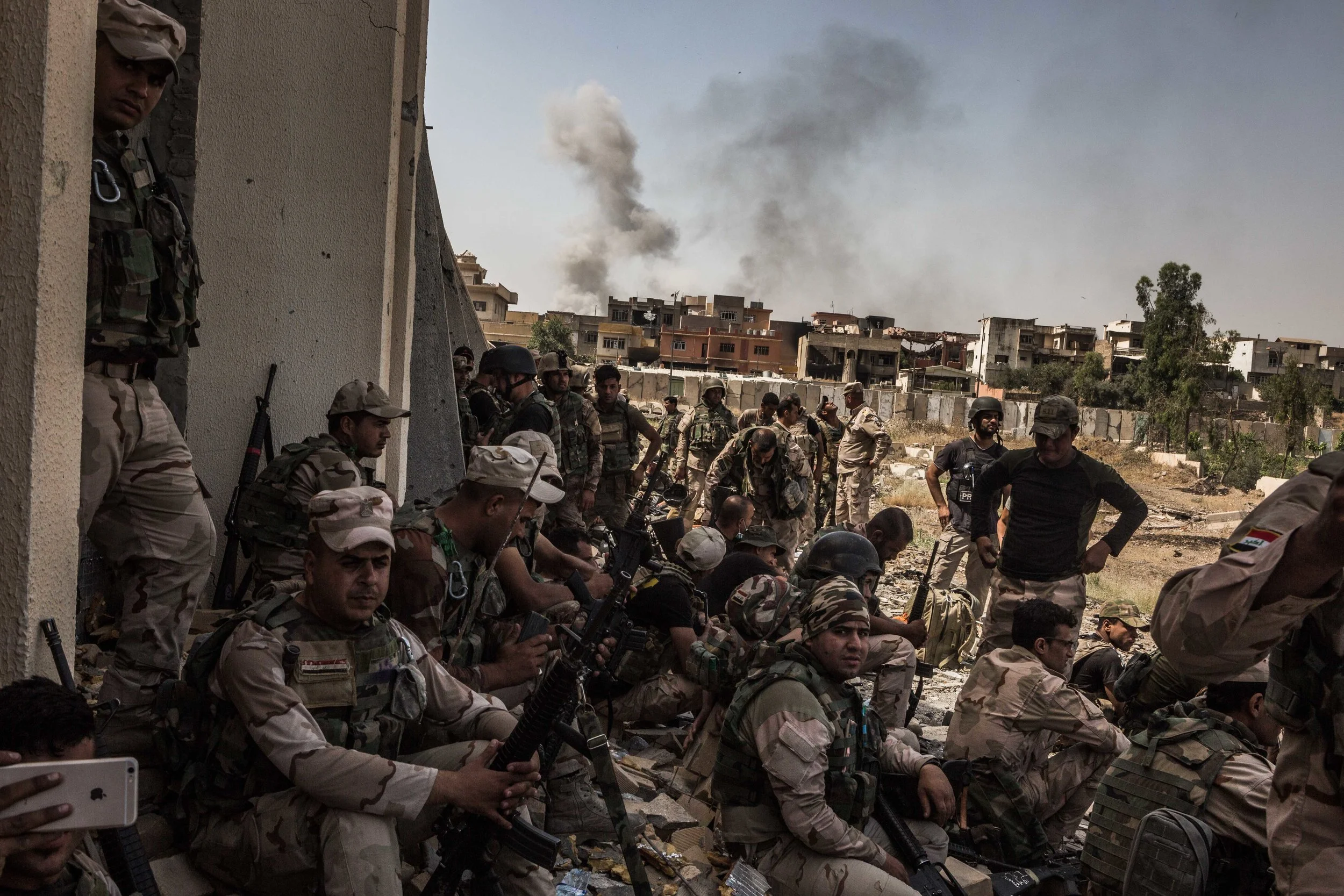 Members of the Iraqi army's 9th and 16th division take cover behind the Old Mosul Hotel as they push forward in al-Shifa neighborhood to retake a large medical complex controlled by the Islamic State in a new northwestern push to rid the militants from the remaining territory of Mosul.