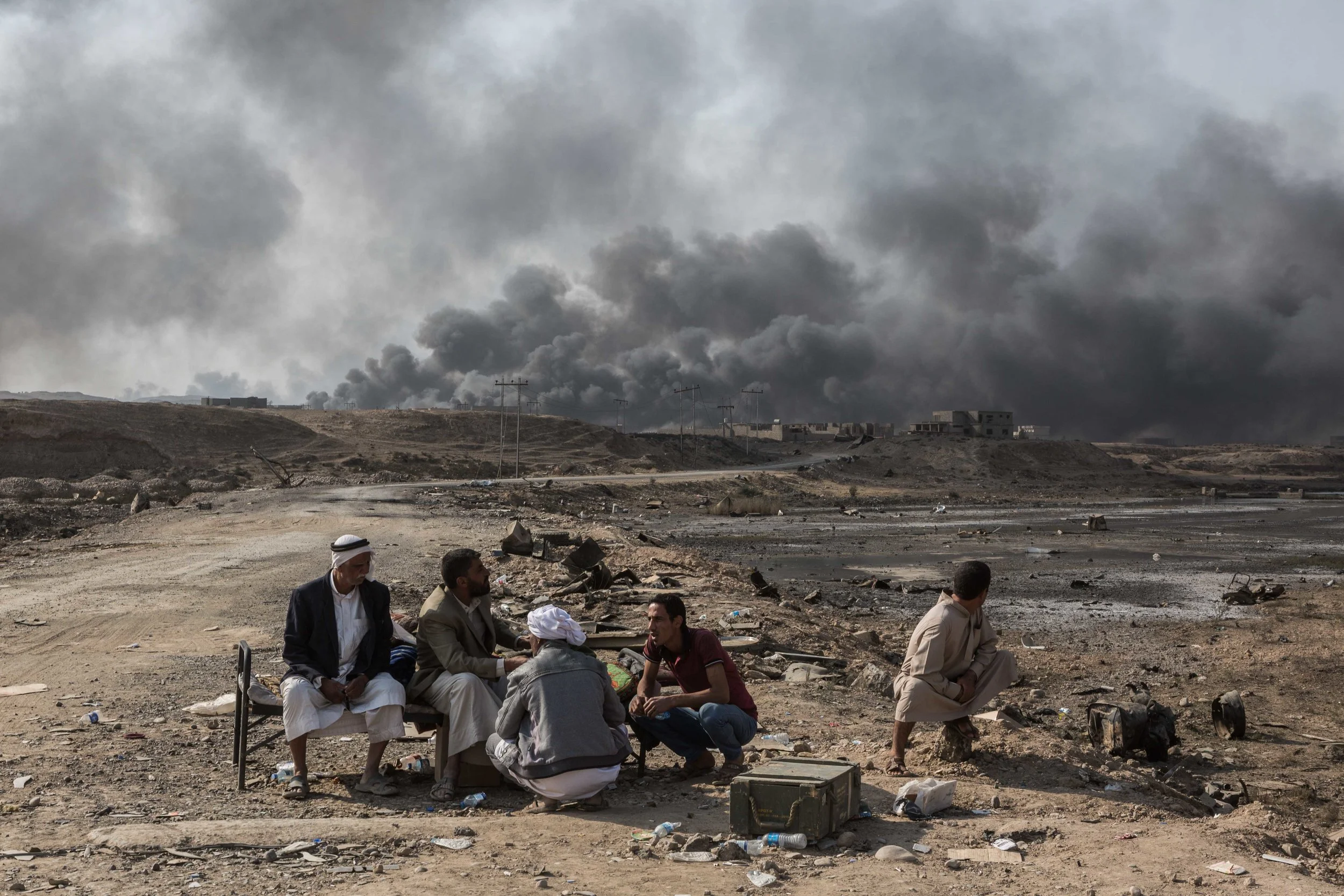 Iraqis fleeing from the fighting between Iraqi army and the Islamic State sit near at a checkpoint to the entrance to the oil rich city of Qayyarah, which was liberated in August 2016 from the Islamic State. Before ISIS left Qayyarah, they lit fire to the oil wells in an attempt to impede the coalitions use of airstrikes on the jihadist group. Analysts have said the smoke plumes do nothing to prevent satellite surveillance used by the coalition forces, but the toxic fumes billowing into the air have caused significant devastation on the landscape and civilian population.