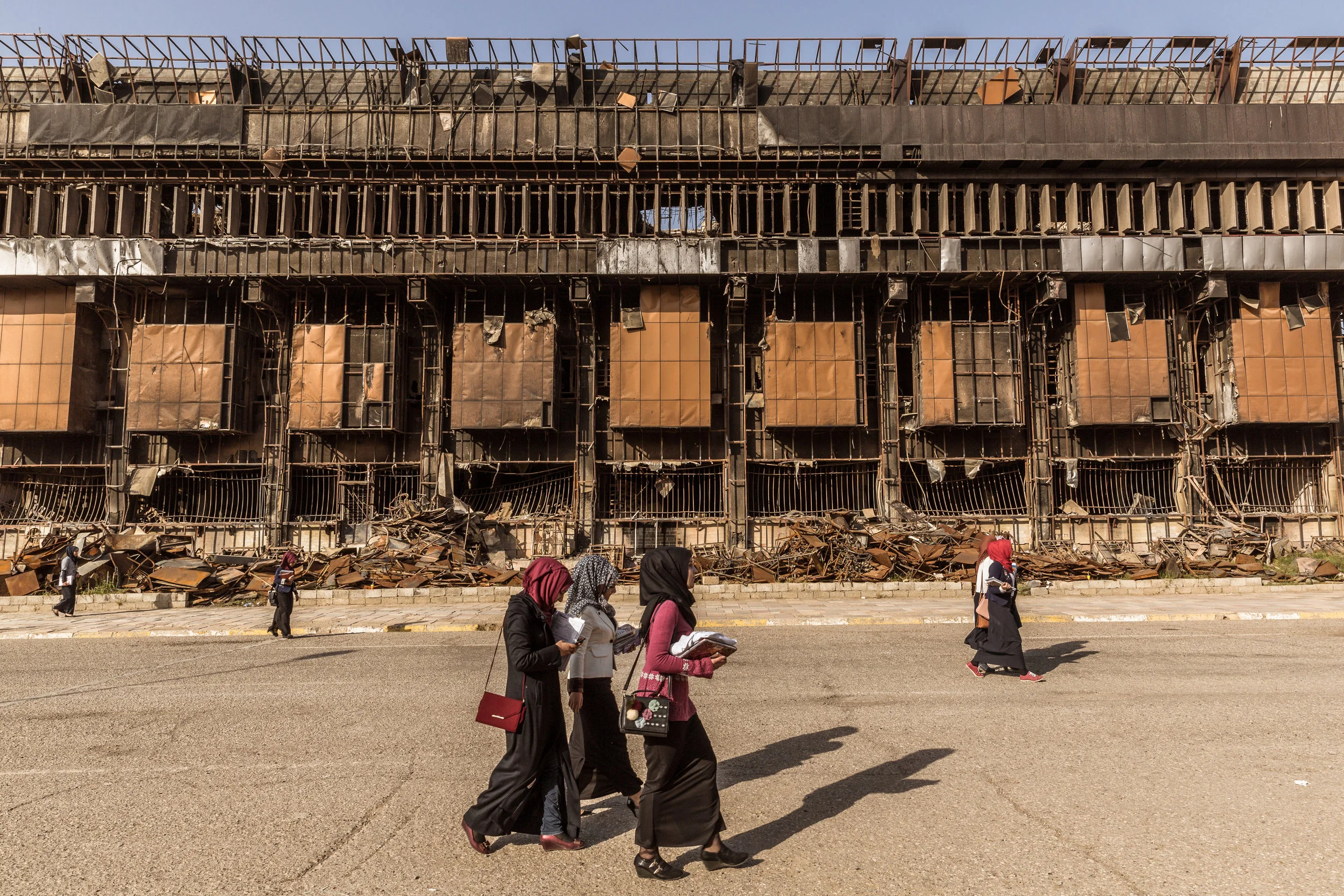 Students walk past the destroyed library at the University of Mosul. After the Islamic State shut down the university, the extremists used the library to produce their own Islamic State teaching manuals as well as classrooms and laboratories as bomb making facilities. In 2017, as federal Iraqi forces were closing in on the group, extremists set aflame the building thinking the smoke would shield them to coalition airstrikes. What little was not destroyed by the group was subsequently destroyed by multiple coalition airstrikes.