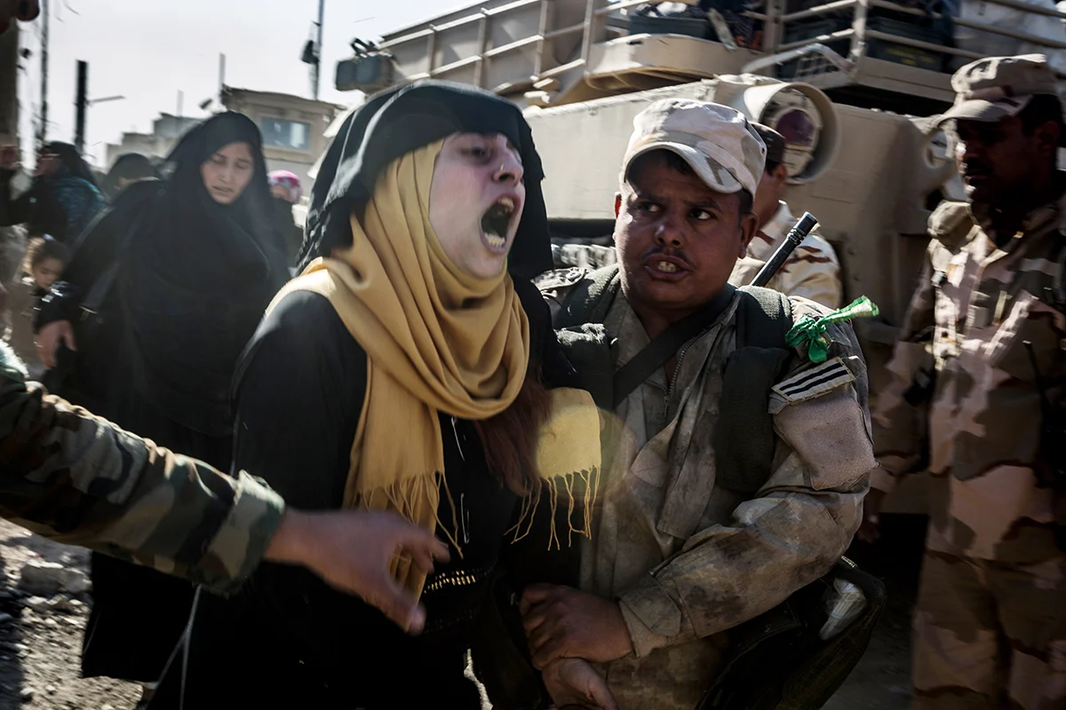 A young woman screams frantically after she crossed the Iraqi Army’s frontline to escape fighting in al-Zinjili neighborhood. Soldiers tried to hold her hands down as she repeated slapped herself in the face. The woman survived a mortar round, sent off by the Islamic State, that struck the group of civilians she was attempting to flee with. Those who were dead, or badly wounded could not be reached beyond the Iraqi frontline.