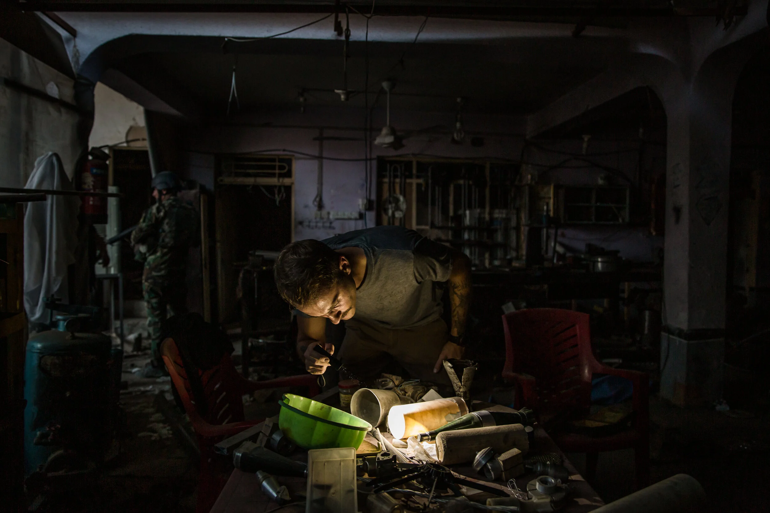 Damien Spleeters pours over half constructed bombs and disassembled rocket parts on a table in a large warehouse in Tel Afar, northern Iraq. The warehouse was recently abandoned by the Islamic State (ISIS). For Spleeters, a field investigator for
