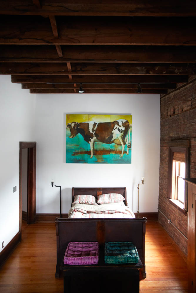 Original americana artwork hangs over the vintage sleigh bed in the Bowler suite.