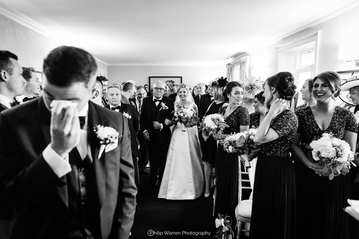 bride and father walking down the aisle towards a crying groom