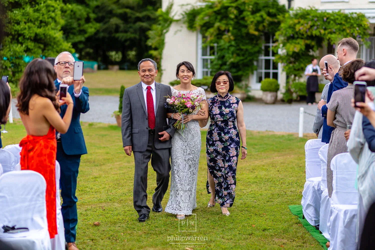 bride walking towards wedding ceremony with her parents