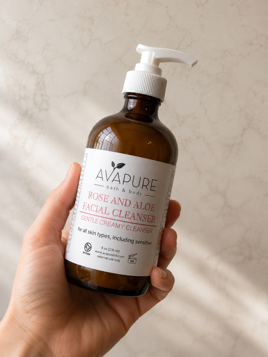 Hand holding Avapure Calm + Restore Cream Cleanser in an amber glass bottle for gentle cleansing of dry and sensitive skin.