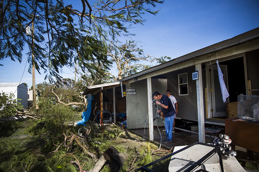 Norm Tabor, a resident of Chokoloskee, sips from a water hose as he helps his neighbor, Michael Kelley, clean up his home after on Monday, September 11, 2017 in Chokoloskee after Hurricane Irma. 