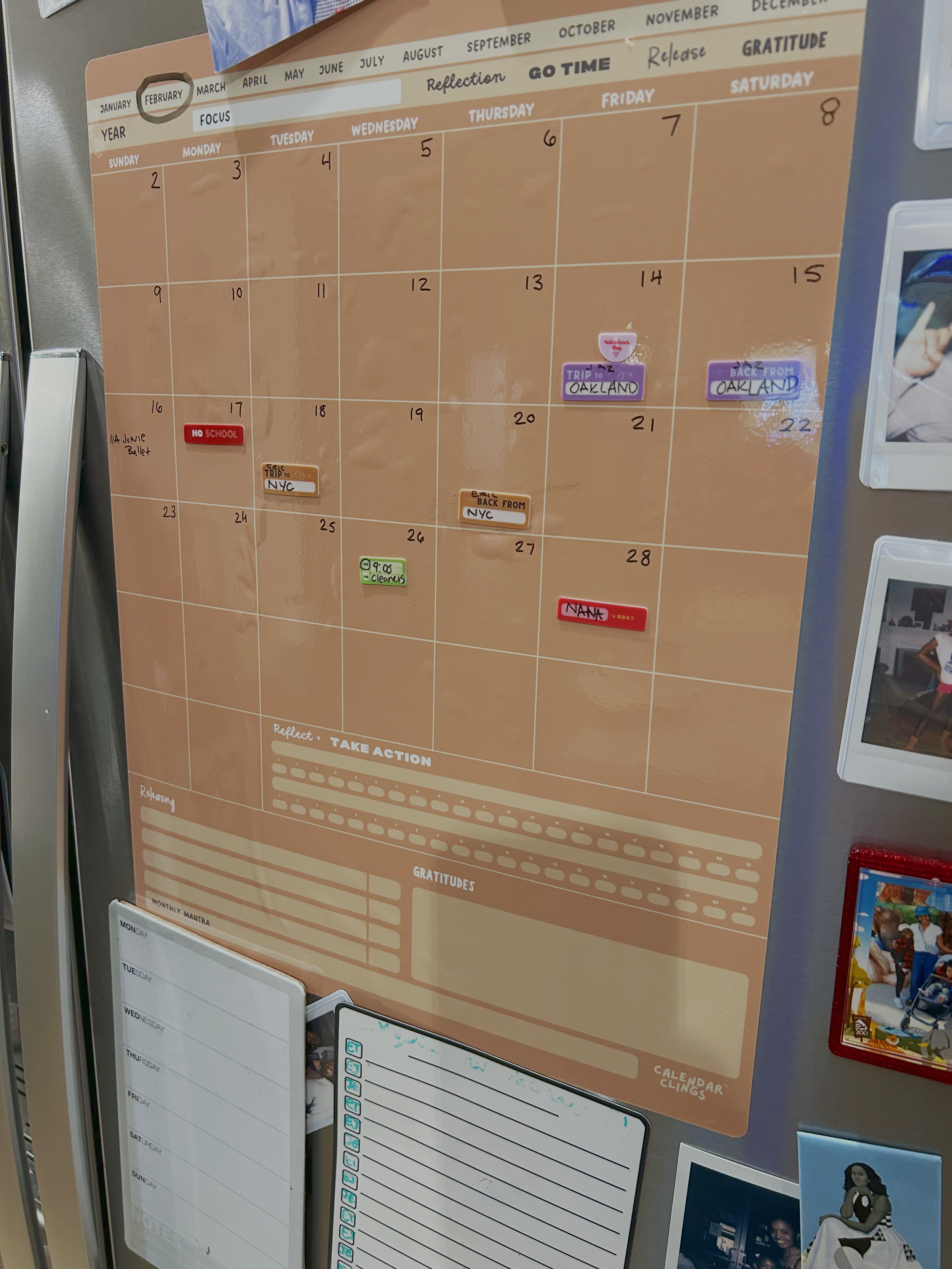 Monthly calendar for February with events such as a trip to Oakland, a trip to NYC, a ballet class, and a birthday. Several stickers and notes are also on the calendar.