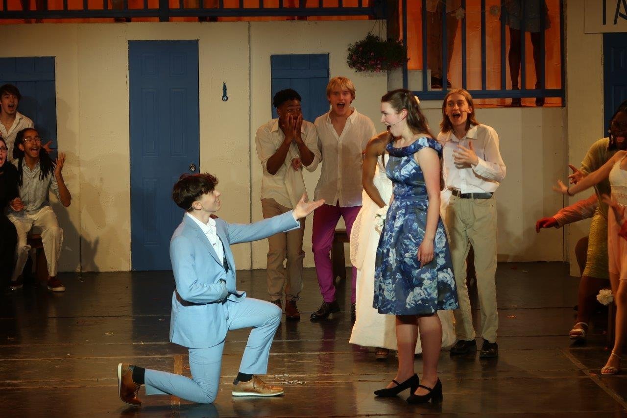  Sam on bended knee in front of Donna and friends in I Do, I Do, I Do, I Do, I Do 