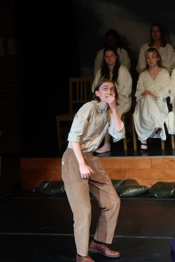  Actor in suspenders looks fearfully upwards as others look on from a distance. 