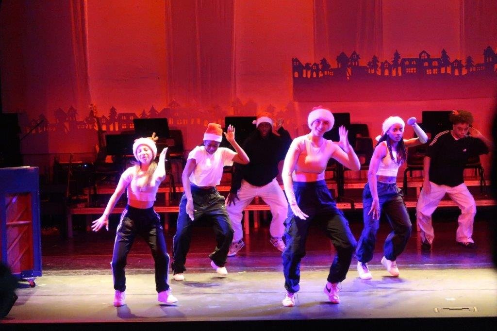  Dancers in white tops and black pants in the foreground, with two dancers in the background in black tops and white pants. 