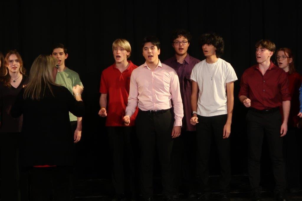  Group of singers singing against a black background. 