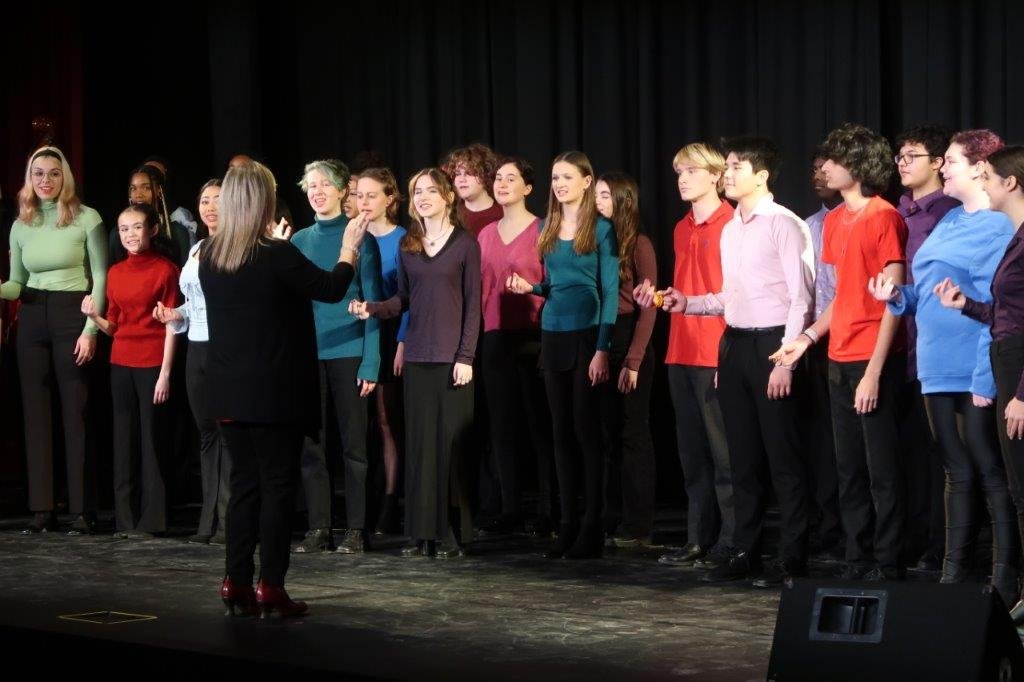  Group of singers singing against a black background. 