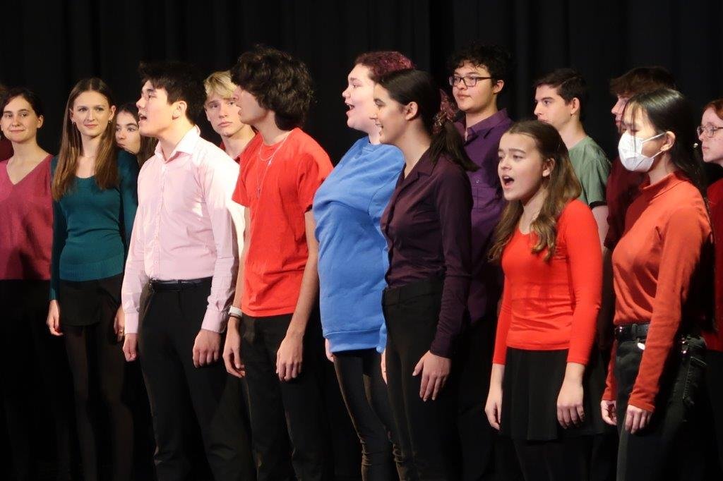  Group of singers singing against a black background. 