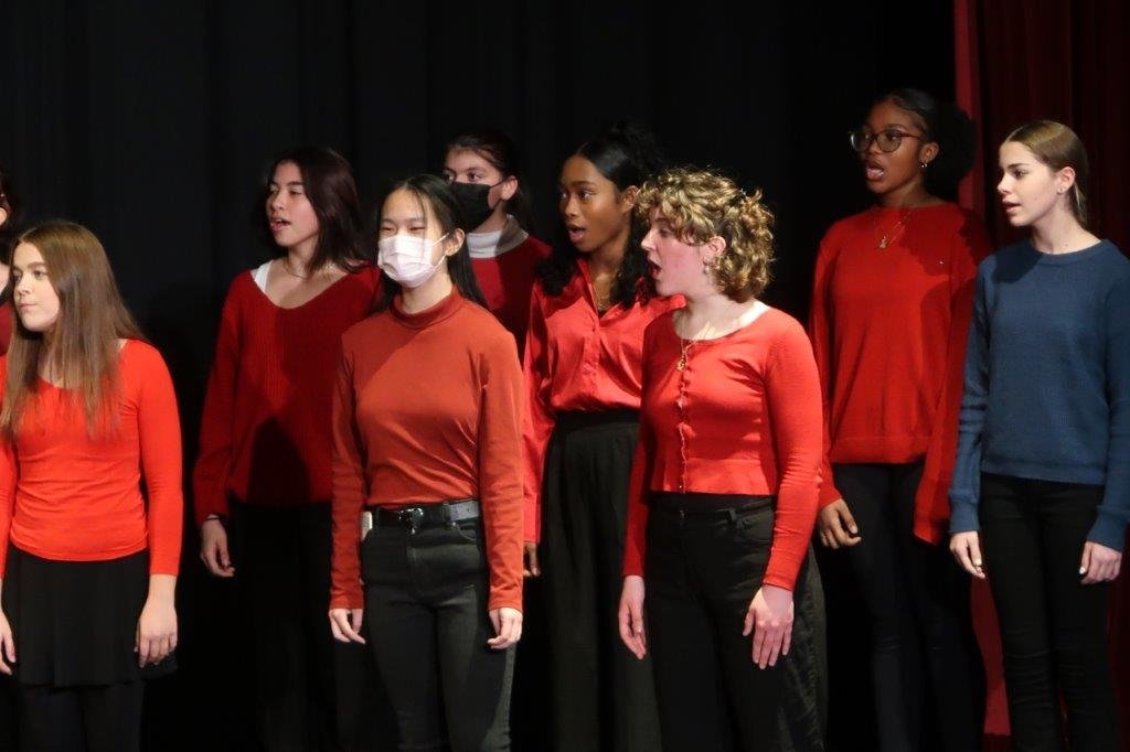  Group of singers singing against a black background. 