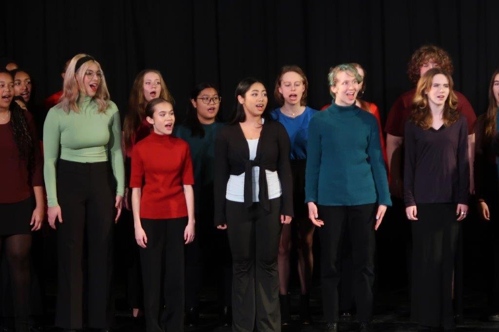  Group of singers singing against a black background. 