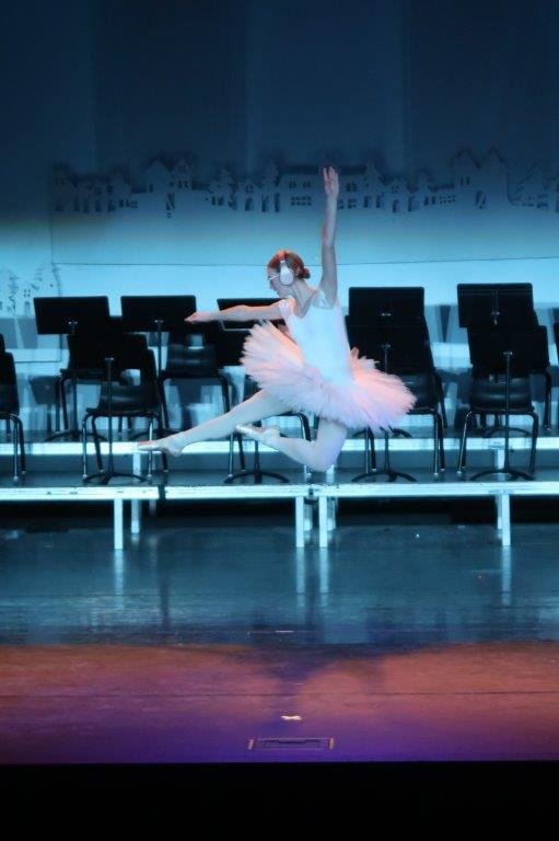  Ballet dancer jumping with legs in the air while having headphones over their head. 