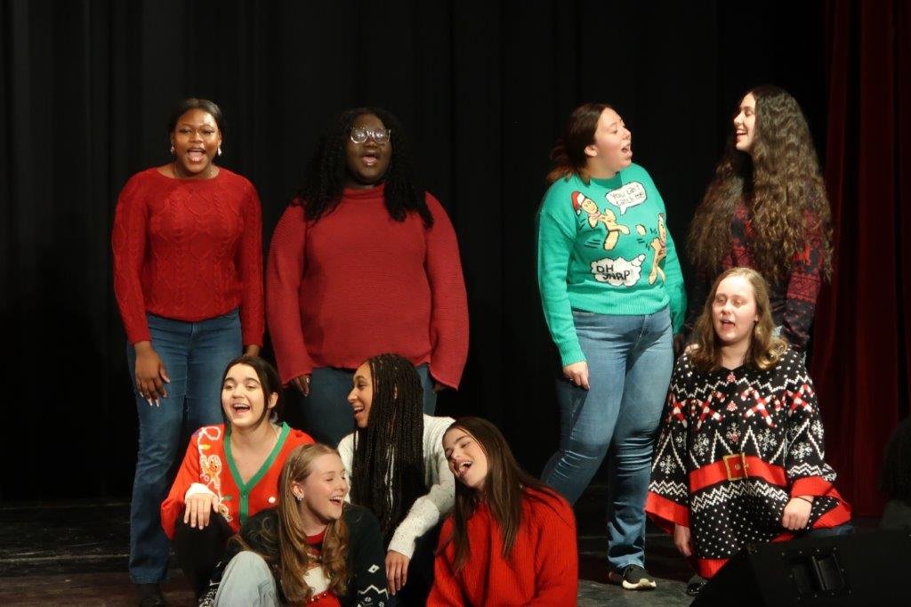  Group of singers singing against a black backdrop. 