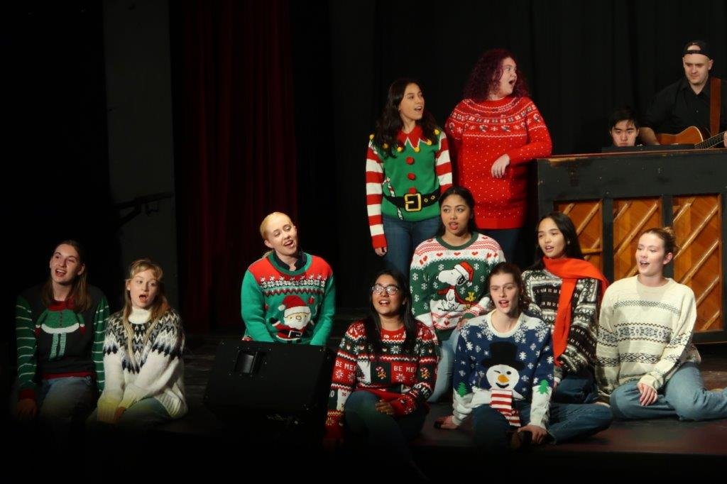  Group of singers singing against a black backdrop. 