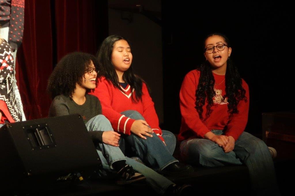  Group of singers singing against a black backdrop. 