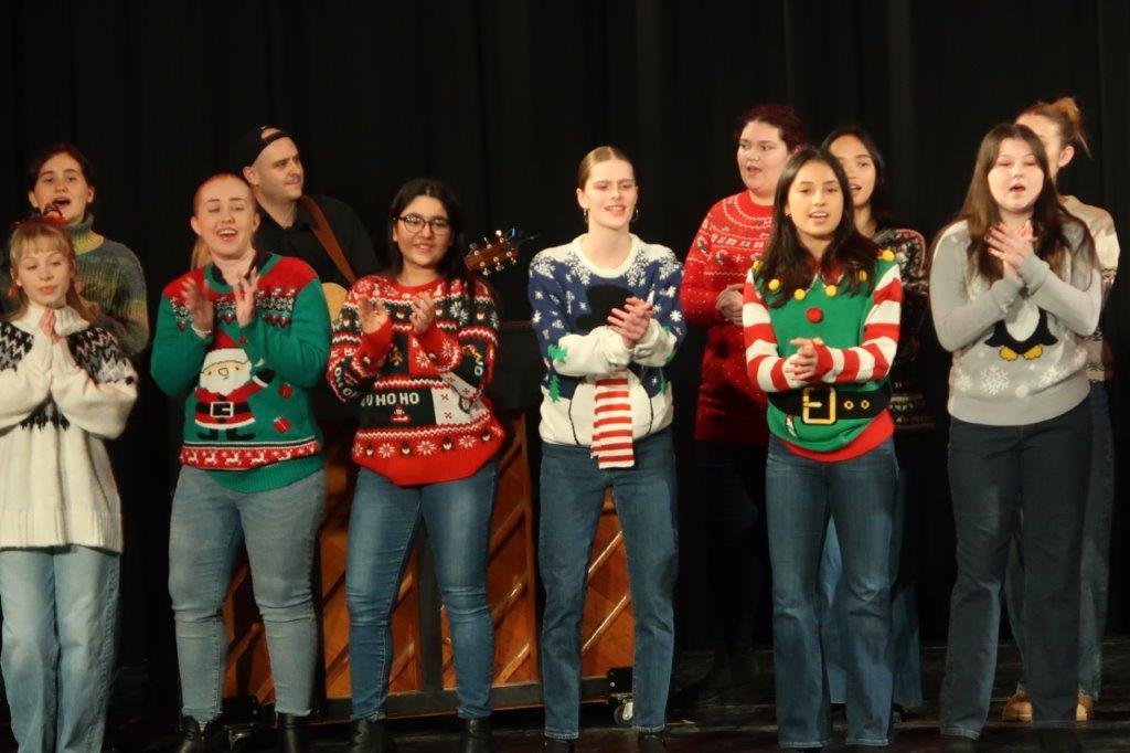  Group of singers singing against a black backdrop. 